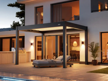 Foto de una pérgola Skydance S3 3x4 Gris Antracita auto soportante en un patio en un atardecer con las luces LED prendidas